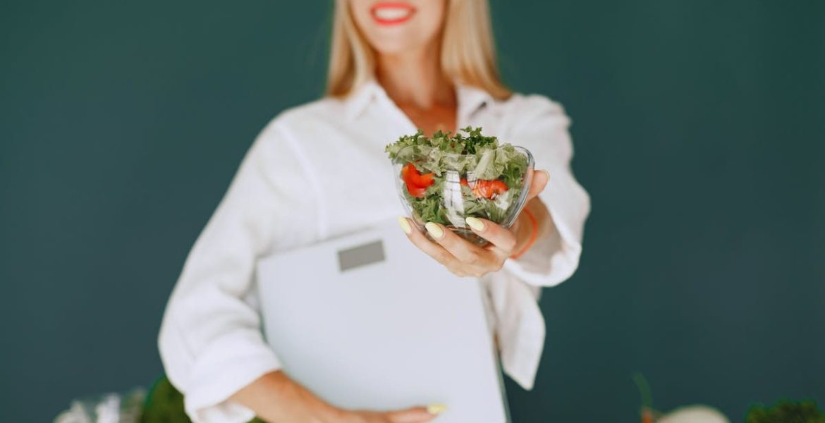 A woman with a vibrant smile offering a fresh salad bowl, promoting healthy eating.
