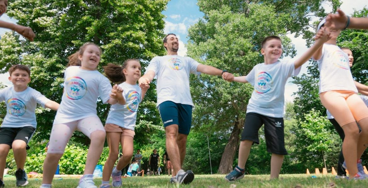 Group of joyful children playing outdoors with an instructor in a sunny park.